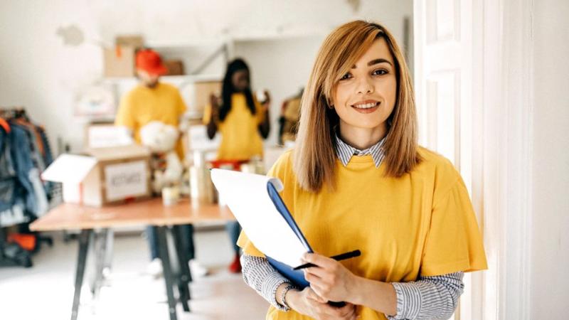 female standing holding clip board